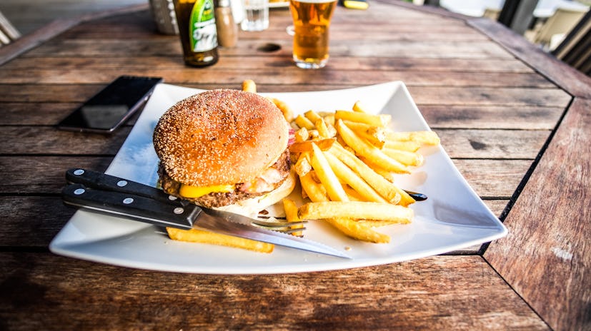A hamburger with fries served on a white plate as a hangover recipe