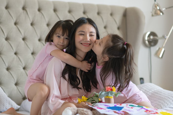 mother and two daughters on mother's day in bed