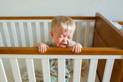 toddler standing and crying in crib