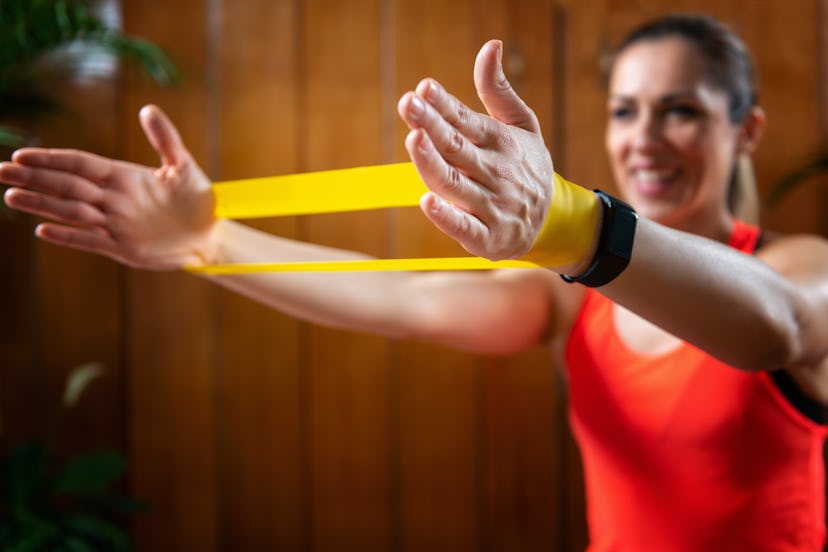A person uses a yellow resistance band to exercise her traps and upper lats. Banded pull aparts are ...