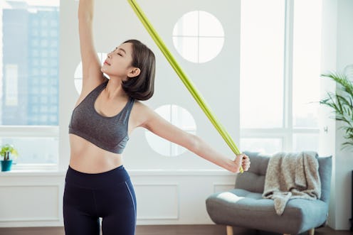 A person holds a behind-the-back resistance band stretch. Resistance band workouts are excellent for...