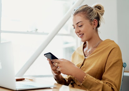 A young blonde lady using a dating app on her phone