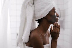 A woman with a towel on her hair taking care of her skin