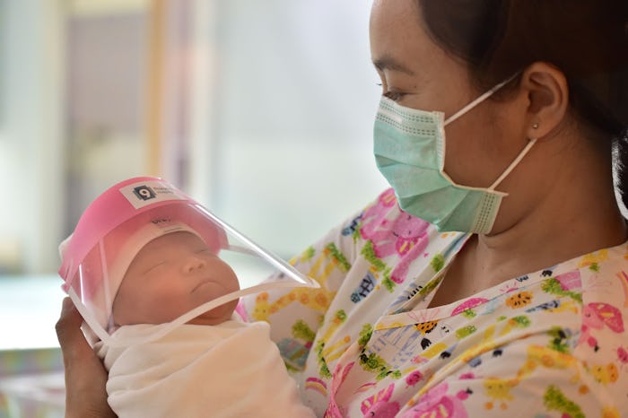 A staffer at a hospital in Thailand holds a newborn wearing a mini face shield to protect them again...