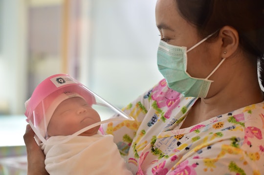 A staffer at a hospital in Thailand holds a newborn wearing a mini face shield to protect them again...