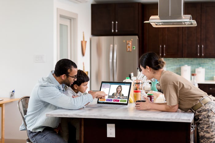 family in kitchen having a distance learning session on computer with teacher