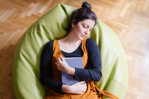 Woman asleep on a beanbag chair clutching a book. If your energy levels are low during the coronavir...