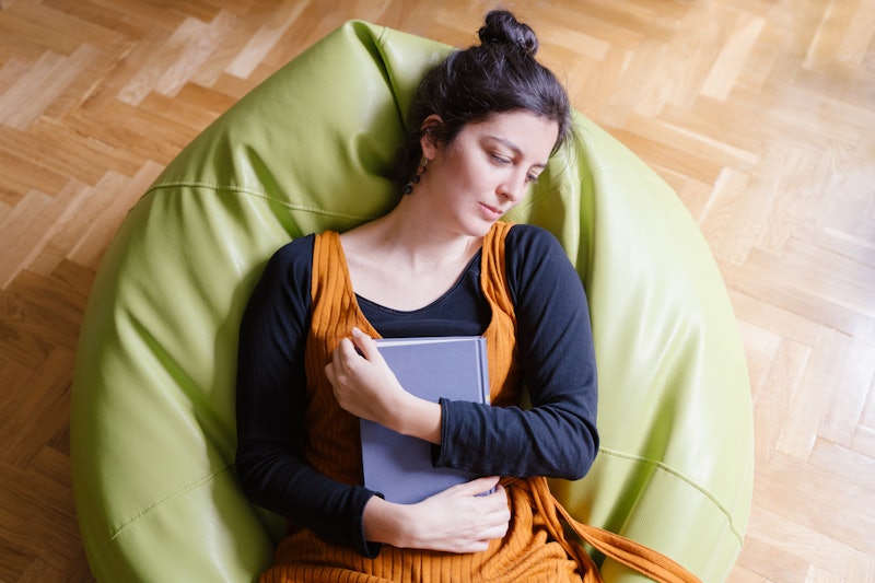 Woman asleep on a beanbag chair clutching a book. If your energy levels are low during the coronavir...