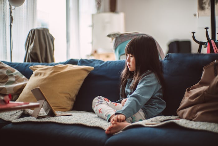 little girl sitting on couch looking at a kindle