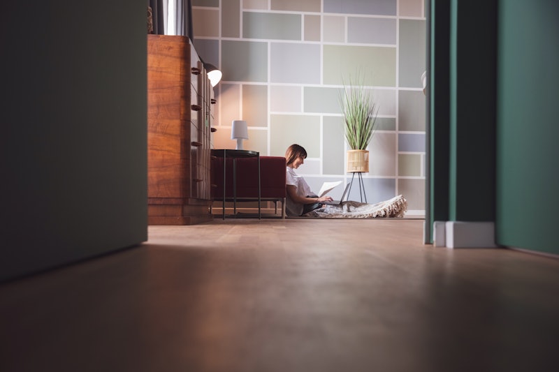 A woman works from home on her laptop while sitting on the ground. Working from home during the coro...