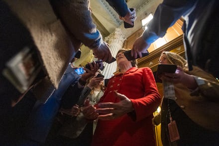 A candidate for the senate in a red suit being interviewed by journalists
