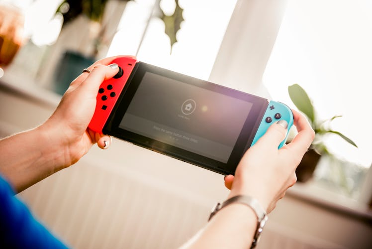 A young woman plays on her Nintendo Switch while hanging out in her apartment on a sunny day.