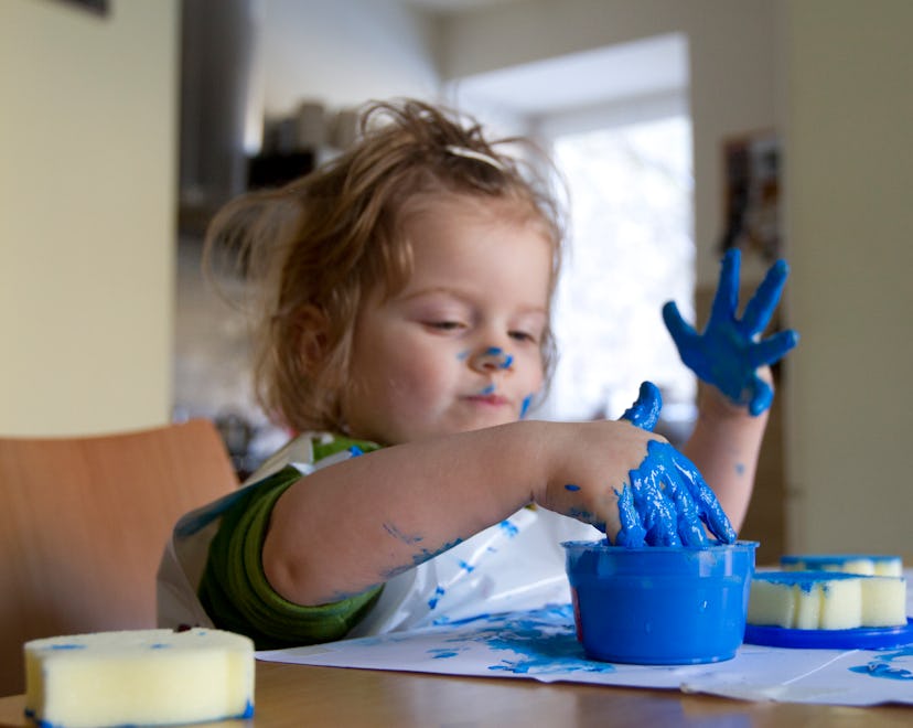 toddler girl making paint handprints