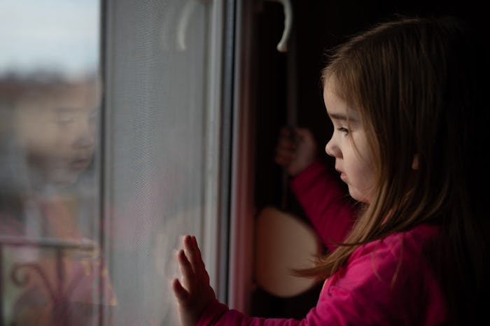 little girl in quarantine looking out window