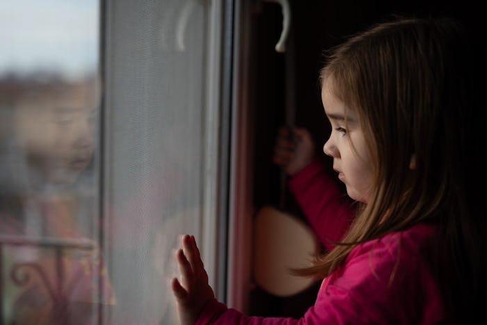 little girl in quarantine looking out window