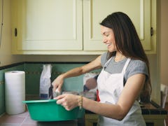 A young woman mixes a cookie dough bread batter in a large, teal bowl in her kitchen.