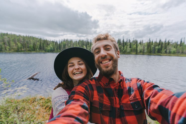 A young couple poses next to a lake while on a summer adventure.