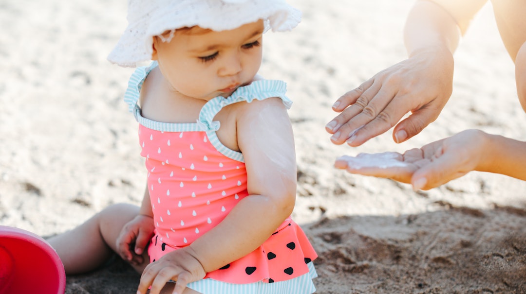 parent putting sunscreen on baby