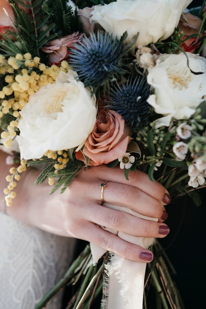 A bride holds a beautiful bouquet of wildflowers on her wedding day.