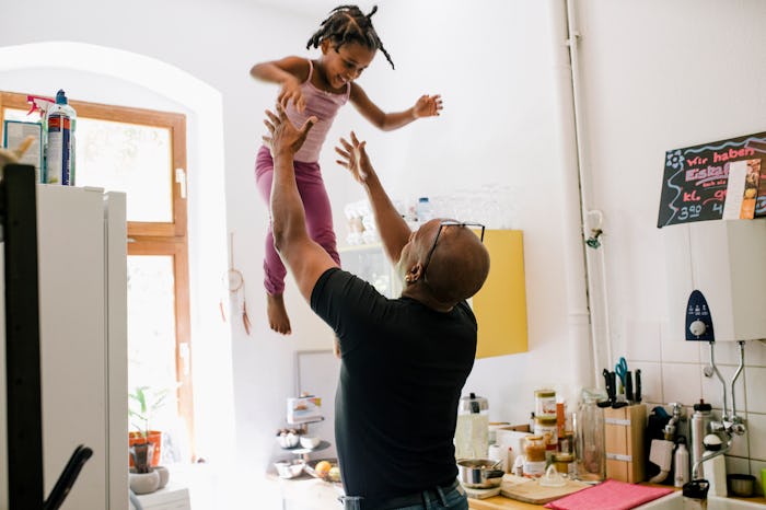 dad tossing his daughter up in the air in the kitchen
