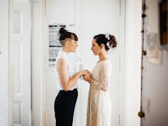 A young lesbian couple stands in a doorway in their home, and recites their vows.