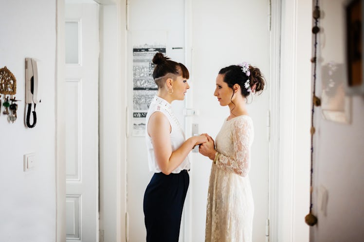 A young lesbian couple stands in a doorway in their home, and recites their vows.