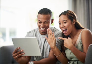 A happy couple shows off their engagement ring on the computer. 