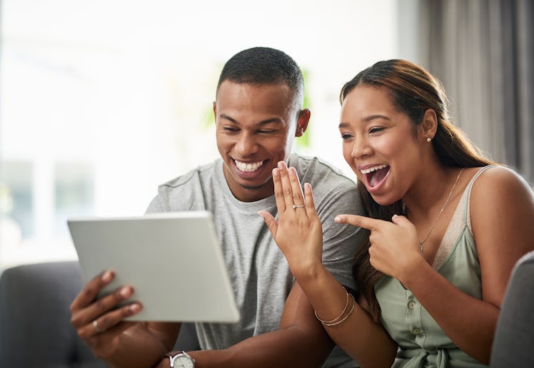 A happy couple shows off their engagement ring on the computer.