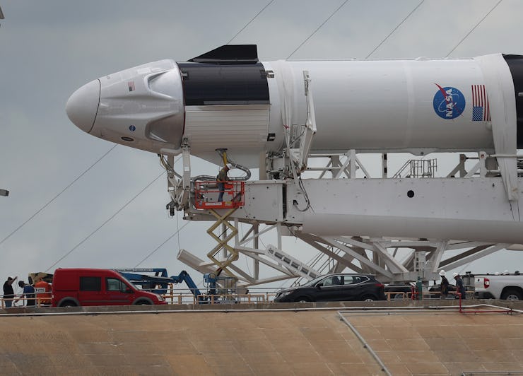 Workers prepare the SpaceX Falcon 9 rocket with the Crew Dragon spacecraft attached for tomorrow's s...