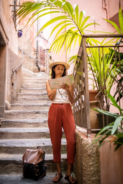 A young woman looks at a map while traveling in Cinque Terre, Italy.