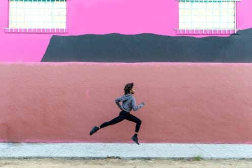 A woman runs in front of a pink building. These free running apps will help you train for a 10k, or ...