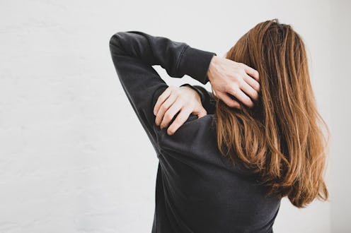 Young woman stretching with her right hand on her shoulder