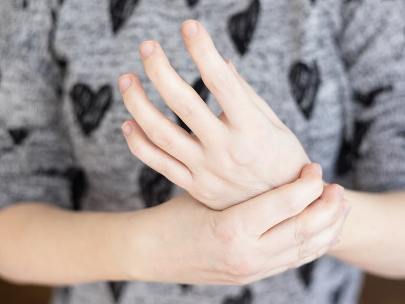 Young lady holding her left hand joint as she experiences joint pain