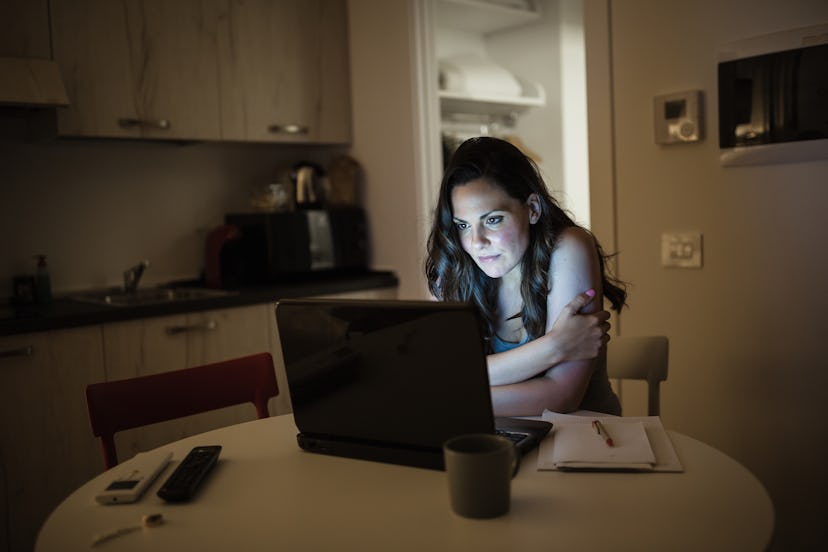 A woman working late on her laptop at night which might be making her being sick