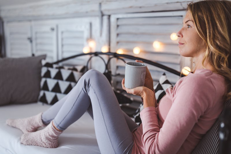 A woman having a drink in a warm and festively decorated sofa