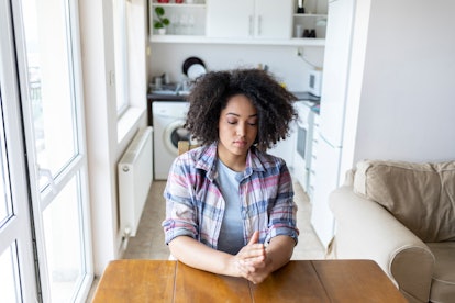 A woman with early signs of lyme disease sitting at a table holding her hands experiencing changes i...