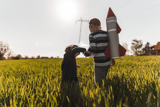 two brothers walking through tall grass with a rocket