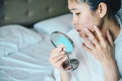 woman checking acne in mirror