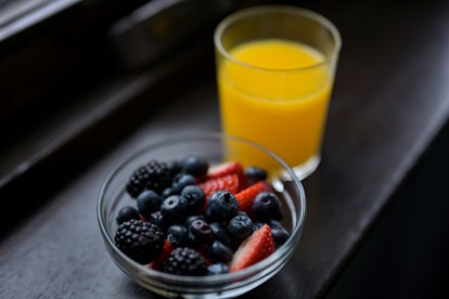 Bowl with blackberries, blueberries and strawberries and a glass of orange juice