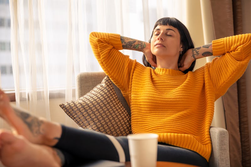 A woman sitting on an armchair pushing her back experiencing early signs of dementia