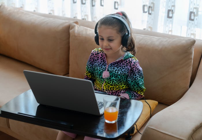 girl sitting on couch wearing headphones in front of laptop