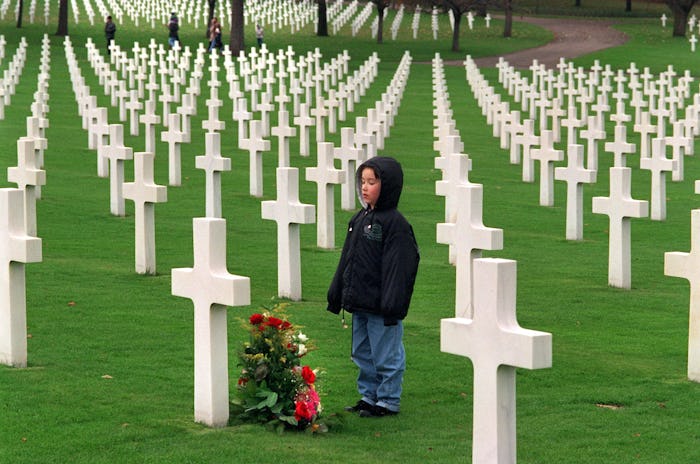 kid standing at a grave in a military cemetery