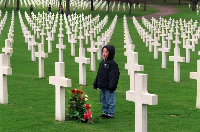 kid standing at a grave in a military cemetery 