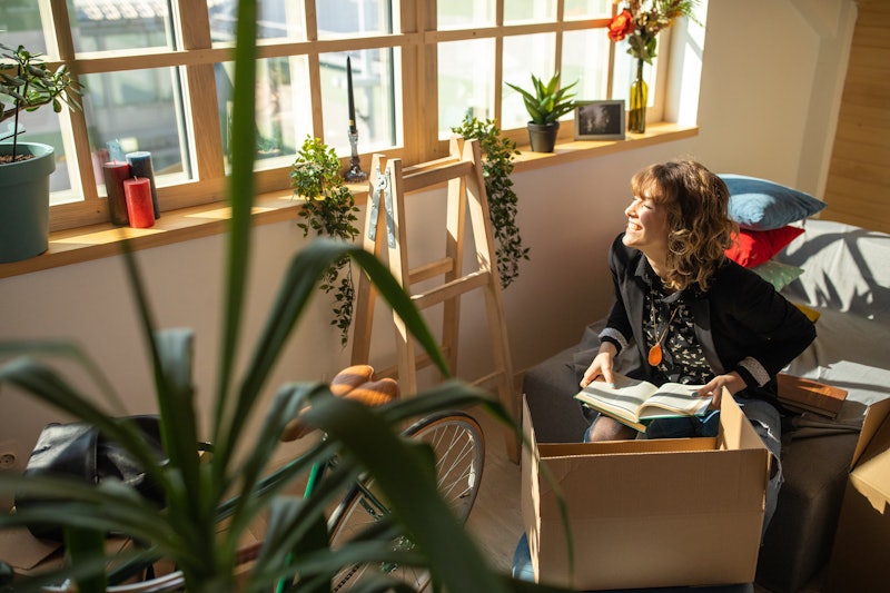 A woman at home unpacks boxes, surrounded by plants. Anxiety About The End Of Coronavirus Lockdown I...