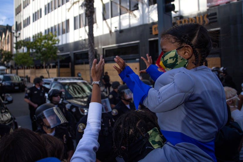 A boy holds his hands up in front of the police