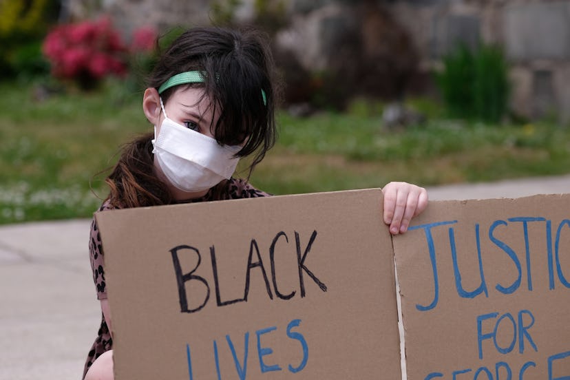 A young girl demonstrates in a mask