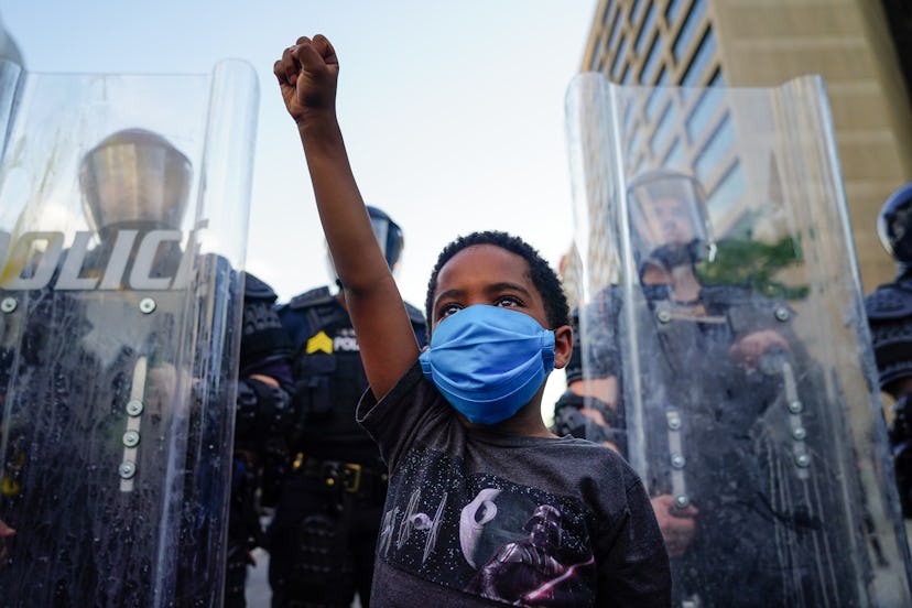 A young boy holds his fist high at a protest