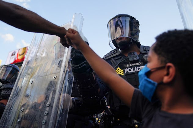 Protestors and police officer fist bump