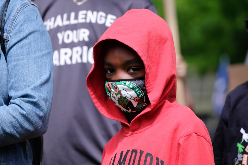 A young boy wears a mask while protesting