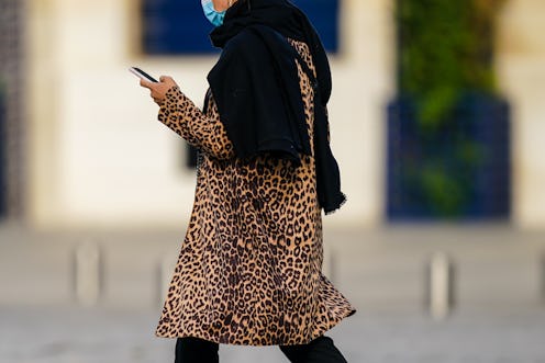 A woman in a headscarf and leopard print wears a facemask. How To Talk To Somebody Who Refuses To We...